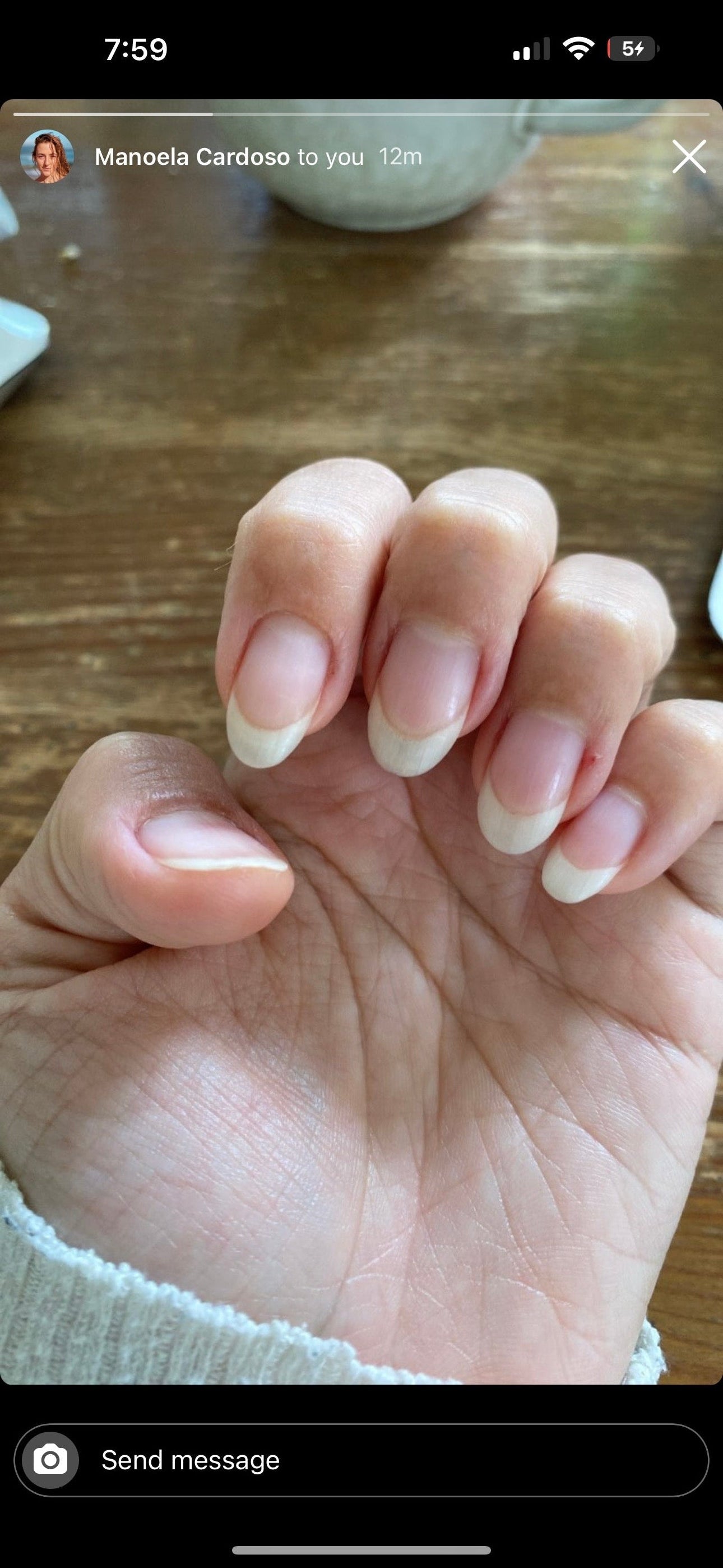 Close-up of a hand with neatly manicured nails on a wooden surface