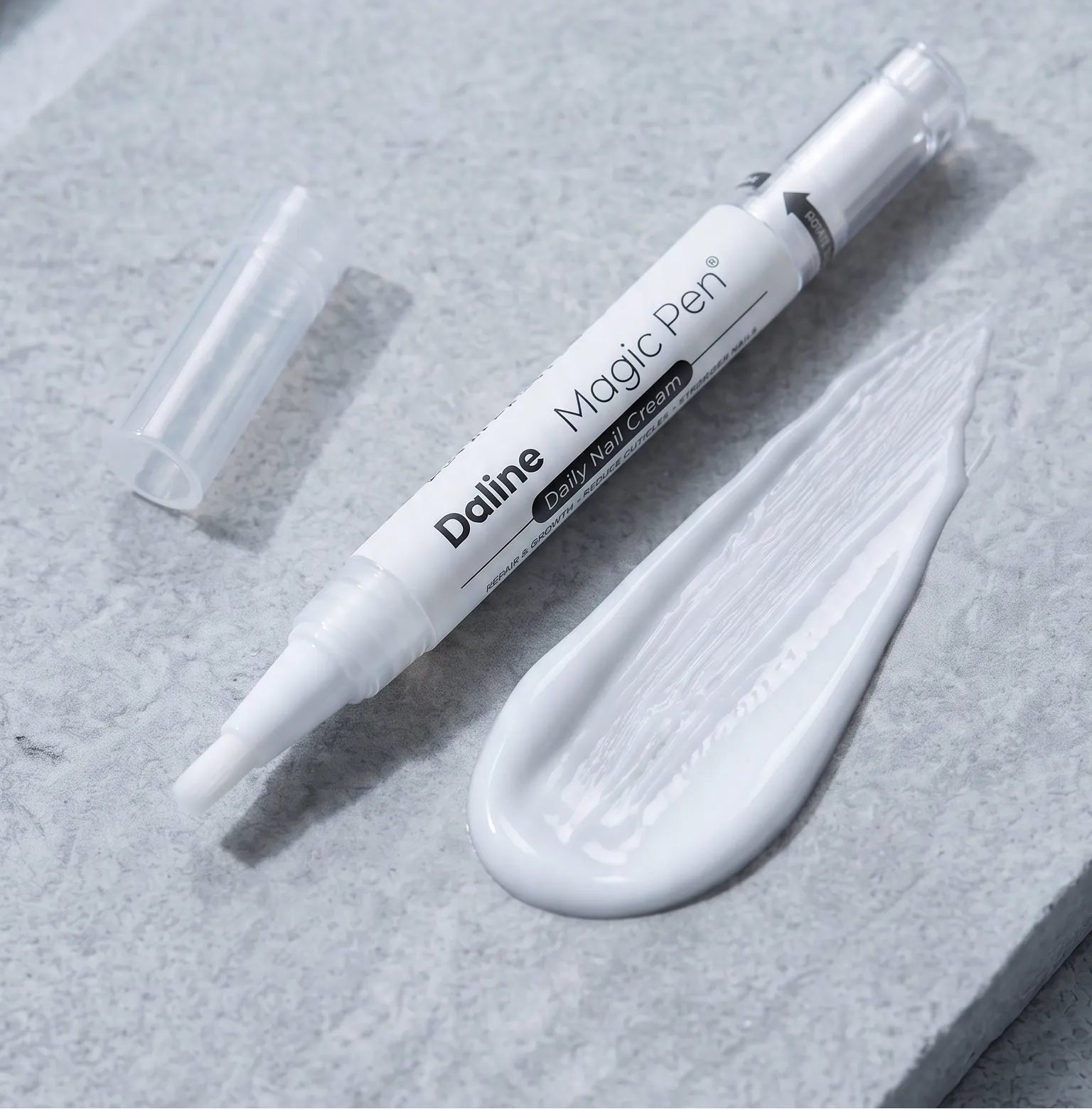 A white Doline Magic Pen cosmetic applicator with its cap off, resting on a textured gray stone surface next to a smear of white cream.